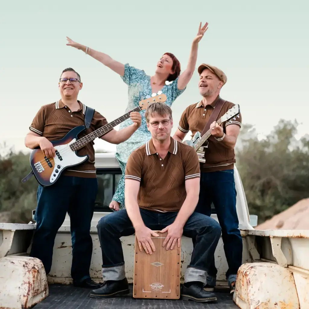 famos. Quartett jubelt mit Instrumenten vor einem Pickup, Conny Morath reißt in der Mitte die Arme hoch